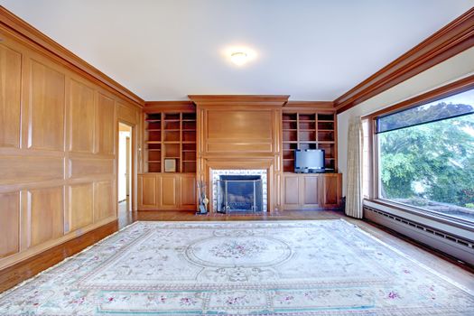 Home office with fireplace, large window and wood walls in luxury old Ameican house.