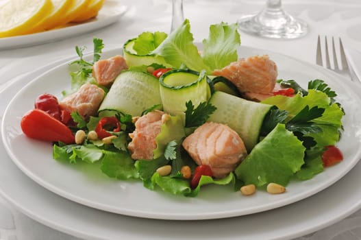 Vegetable salad with boiled salmon and pine nuts