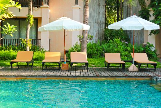 Beach chairs and umbrella side swimming pool