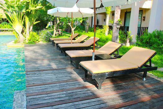 Beach chairs and umbrella side swimming pool