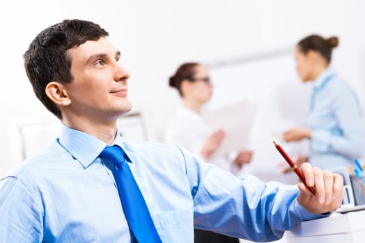 Portrait of a businessman in a blue shirt in the background of colleagues discussing