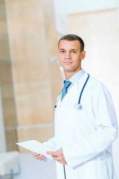 Portrait of a doctor holding papers in hand, office space