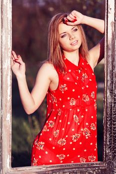 Beautiful woman in a red dress in burnt window