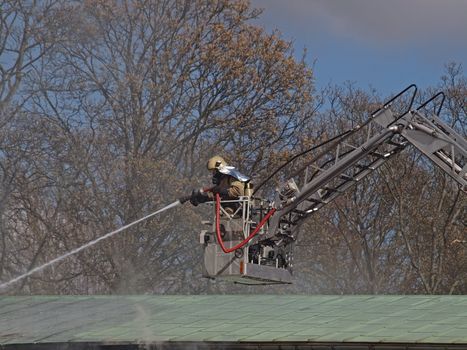 fireman on crane extinguishing fire above the roof