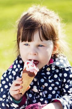 little girl eats ice cream on the street