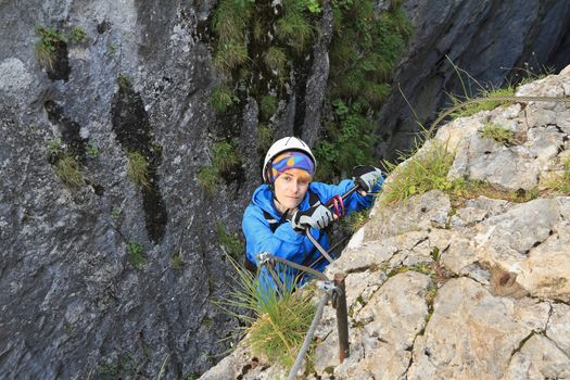 female climber with white helmet on via ferrata, italian Dolomites