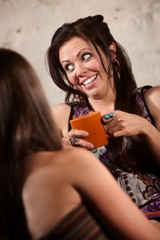 Laughing Caucasian brunette female sitting with friend indoors