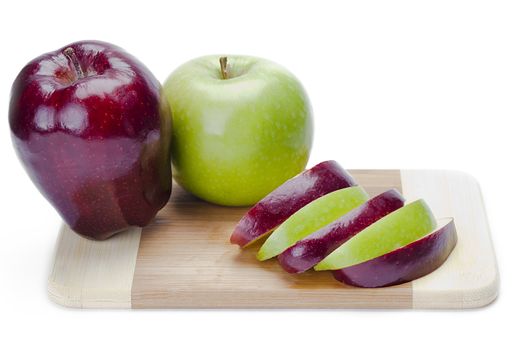 Mixed apple slices on a wooden cutting board, isolated on white.