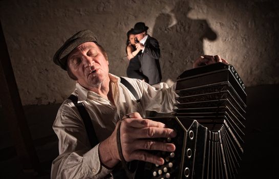 Singing bandoneon player with two dancers in the background