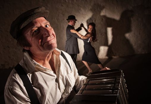 Smiling accordion player performing with dancers in the background