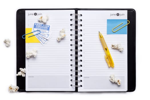 Image of notebook organizer with paper clips, pop corn, ball pen against white background
