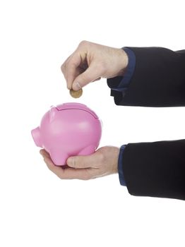 Human hand holding coin over pink piggy bank against white background