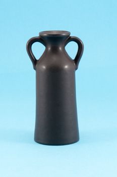 old ceramic black vase with two handles on blue background.
