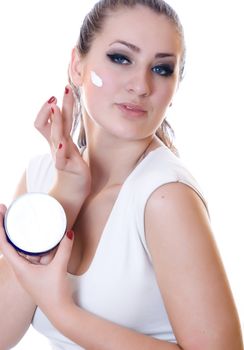 Portrait of young beautiful woman applying moisturizer cream on her face, isolated on white background