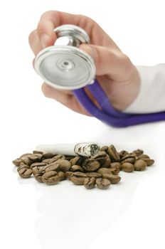 Male hand holding stethoscope over cigarette on coffee beans. Concept of help for smoking addiction.