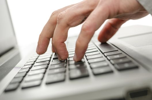 Male hand typing on laptop keyboard.