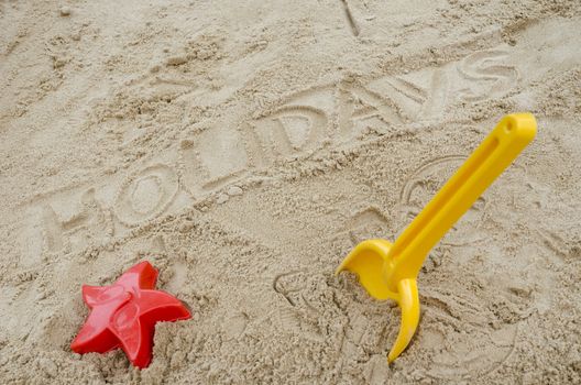 Word holidays written in sand. Concept of happy summer holiday.