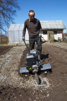 Middle age man with a rototiller in the garden 
