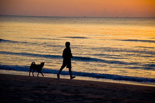 silhouette of man running on the beach with dog