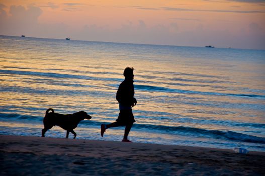 silhouette of man running on the beach with dog