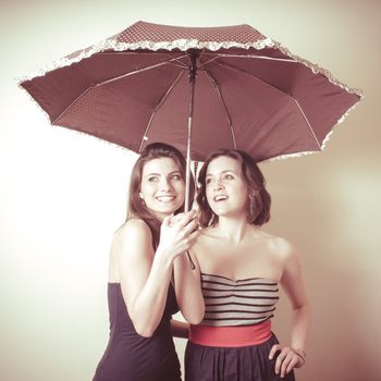 vintage portrait of two young women with umbrella on white background