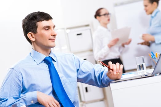 Portrait of a businessman in a blue shirt in the background of colleagues discussing