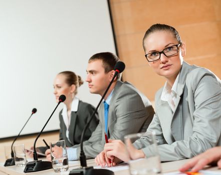 businessmen communicate at the conference, sitting at the table, on the table microphones and documents