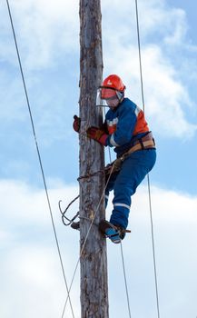 electrician climbs a power pole with the use of claws- manholes and  belt
