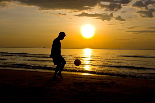 silhouette of man play soccer on the beach