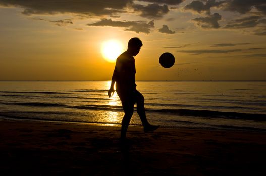 silhouette of man play soccer on the beach