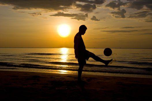 silhouette of man play soccer on the beach