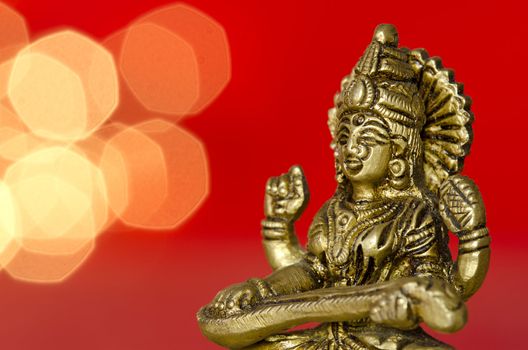 close up of a Hindu deity statue with lights in the back on red background