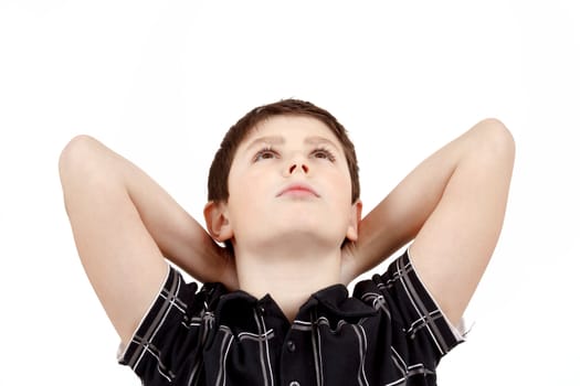 Portrait of boy on white background, smiling, he looks up with his hands behind his head. 