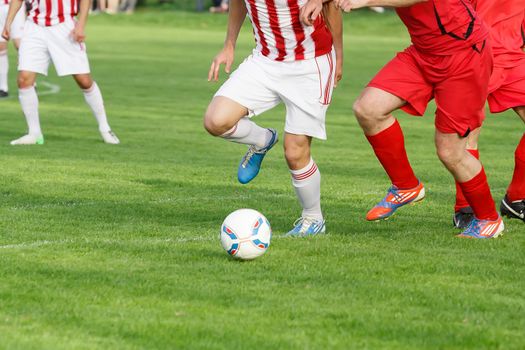 Soccer player legs dribbling in a match on green grass