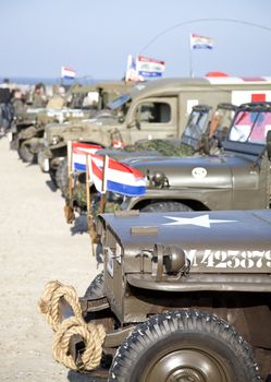IJMUIDEN, THE NETHERLANDS-MAY 5 2013: Army trucks of organization Kelly's Heroes riding on beach on May 5,2013 in IJmuiden, The Netherlands. Simulate arrival of allies on liberation Second World War