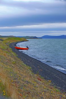 Iceland landscape with red boat on Myvatn lake in northern Iceland. Vertical view