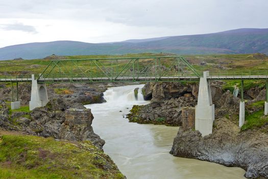 Summer Iceland landscape with big mountain river with bridge.