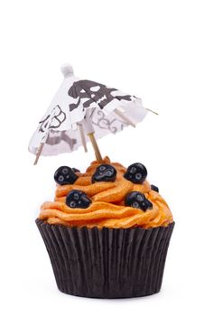Close-up image of a orange cupcake with skull topping and canopy with skull design over white background.