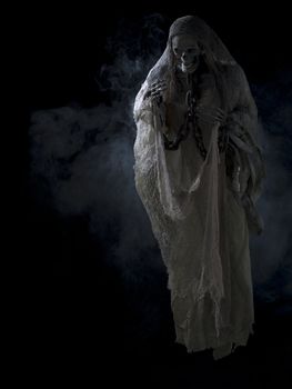 Image of a human skeleton surrounded with smoke over dark background.