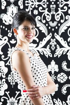 young woman in front of a black and white textured background with 60's inspired style with great big smile