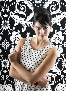 young woman in front of a black and white textured background with 60's inspired style with serious expression