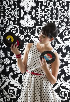 young woman with stylist clothes, curious about three small record