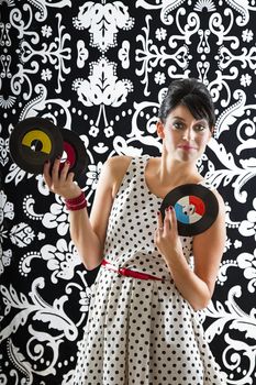 young woman with stylist clothes, with a intrigue expression at three small record