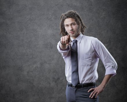 Young business man in suite, pointing at camera
