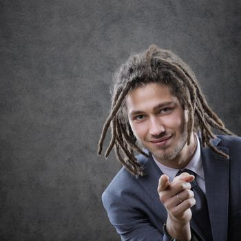 Young business man in suite, pointing at camera