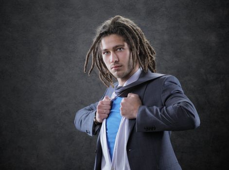 Young man dressed in suit, shirt and tie pulling open shirt 