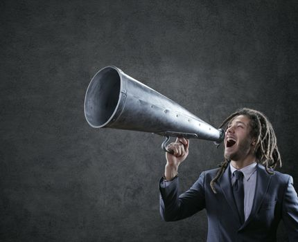 Young businessman yelling trough a vintage megaphone