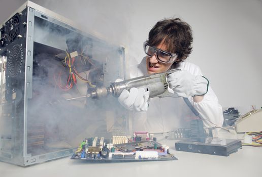 Crazy computer technician is trying to repair a computer with a drill