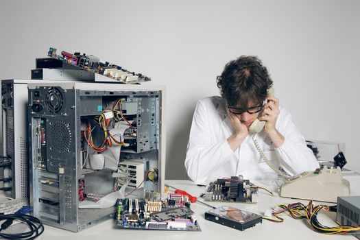 Computer technician in his laboratory is talking on the phone