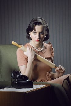 Angry wife waiting for her husband with a rolling pin in hand